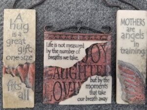 3 Small Signs:  “Mothers are angels in training” /  “A hug is a great gift, one size fits all”  /  “Life is not measured by the number of breaths we take, but by the moments that take our breath away”