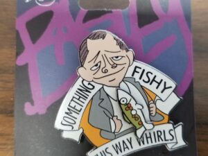 2002 Olympic Pin — “Something Fishy This Way Whirls” — Utah Pins — “100% bona fide Bagley Pin” — “Salt Lake Tribune cartoonist Pat Bagley gets his pin ideas from celibate polygamist monks who mountain bike to work in Moab, Utah” — New Condition